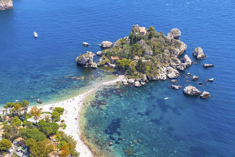 Isola Bella in Taormina, Sicily, with clear water, rocky coast and a small beach below the island.