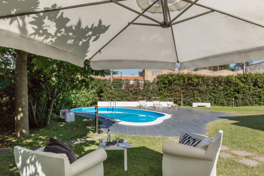 Sitting in the garden in the shade of a sun umbrella with a view of the swimming pool.