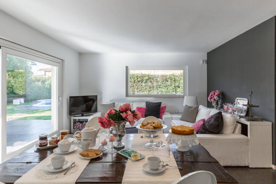 The dining table between the kitchen and the TV area, which overlooks the veranda through a wide glass window. 