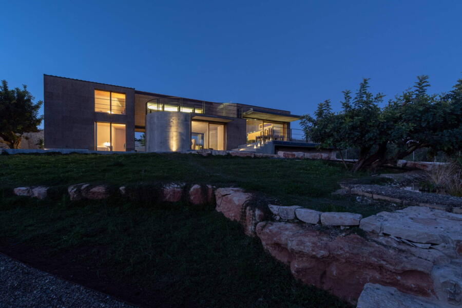 The evening lights highlight the refined structure of the villa