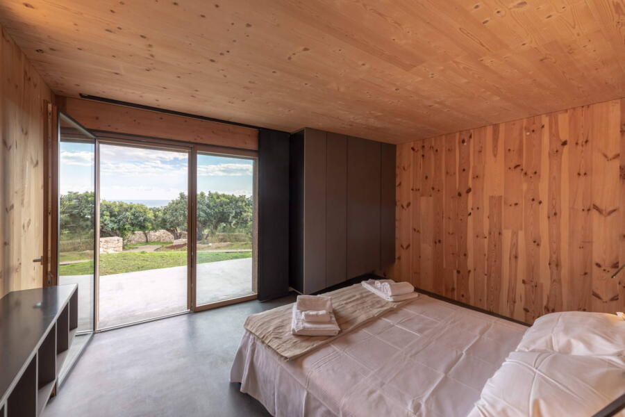 The neutral materials used in the bedroom and the nature that can be seen through the large windows.