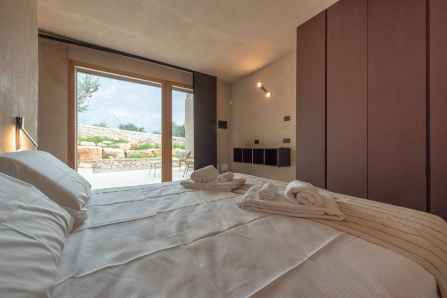The double bedroom overlooks its veranda surrounded by nature that can be seen through the large windows.