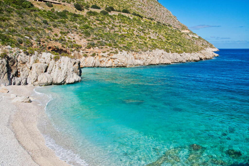 A stunning view of the clear turquoise waters and rugged cliffs of Riserva dello Zingaro in Sicily, Italy.