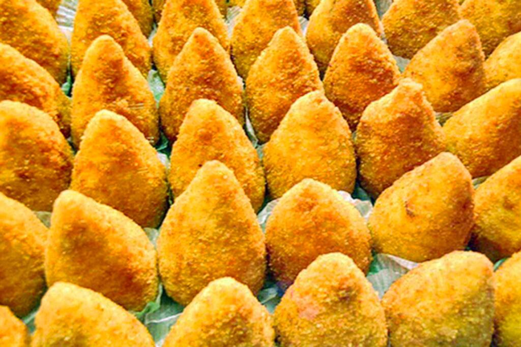 Close-up image of Sicilian Arancini, golden-fried rice balls filled with ragù, mozzarella, and peas.