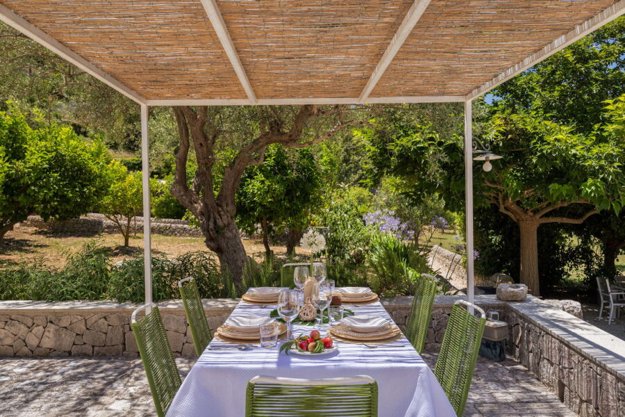 Inviting outdoor dining space under a pergola at a Sicilian villa with pool.