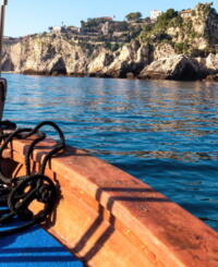 Tourist boat offering a sweeping view of the picturesque coastline near Isola Bella in Taormina, Sicily, with the tranquil turquoise Ionian Sea as backdrop.