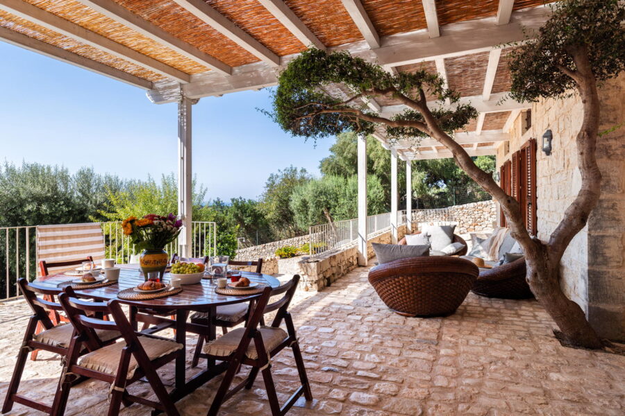 View of Villa Cudiano's patio overlooking the pool and the sea in Sicily.
