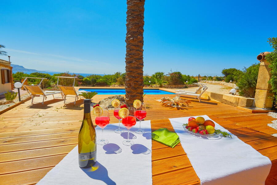Table set for a poolside meal with scenic views at a Sicilian villa.