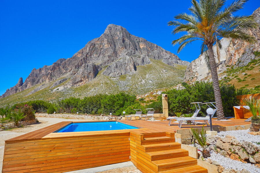 Peaceful poolside setting against a backdrop of Sicilian mountains.