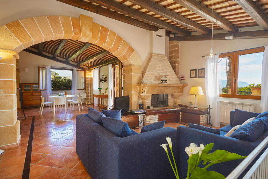 Bright living room with arched ceiling and fireplace in a Sicilian villa.