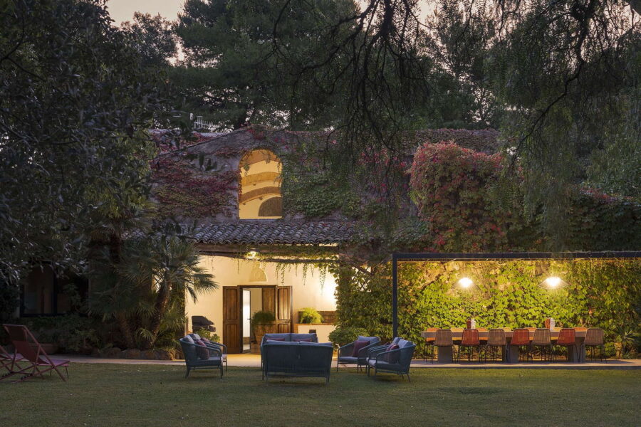 Twilight view of the garden lounge and outdoor dining area surrounded by ivy-covered walls and soft lighting at Villa Selvira, a top Sicily villa with pool.