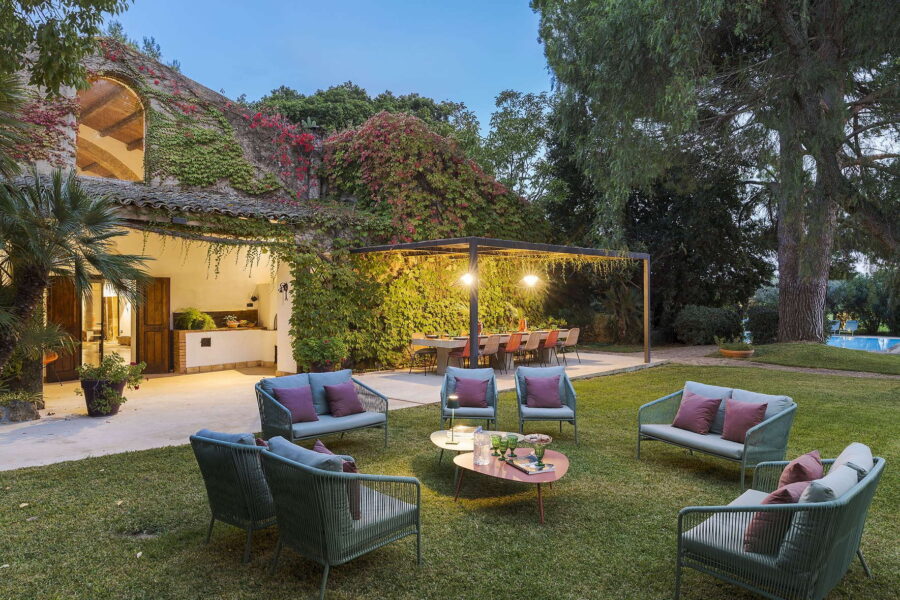 Outdoor dining area under a pergola and garden seating with ivy-covered villa walls at Villa Selvira, luxury accommodation in Sicily with pool.