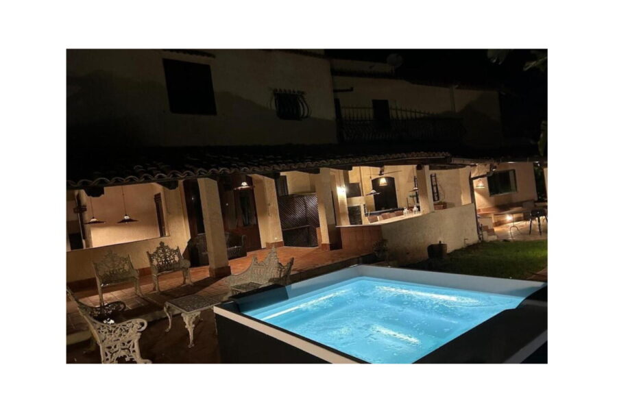 Nighttime view of Villa Fontane Bianche in Sicily featuring a glowing Jacuzzi and traditional outdoor lounge area.
