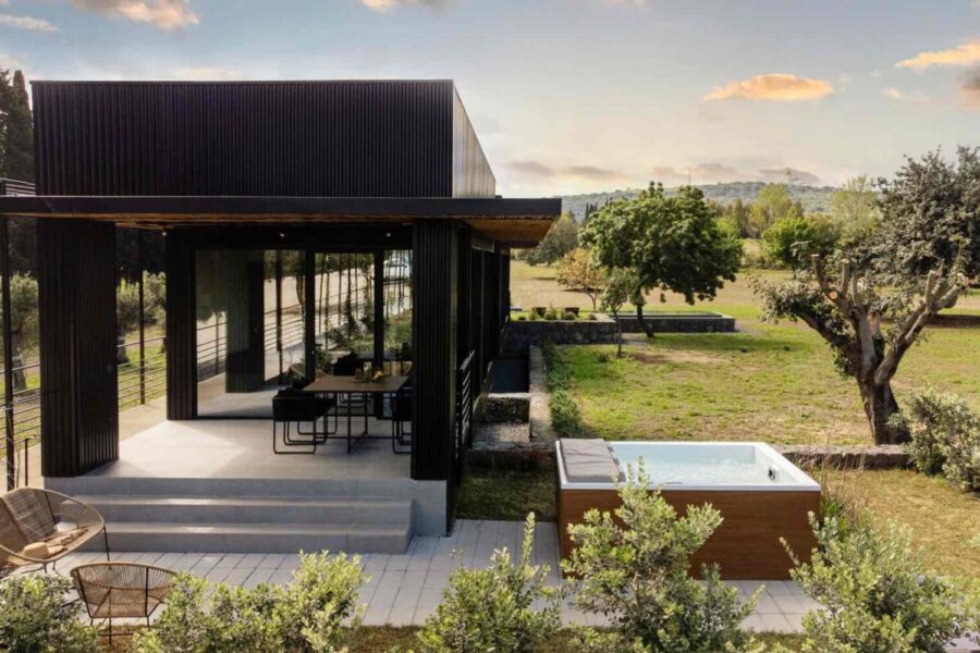 Modern black villa with a private jacuzzi and outdoor dining space at sunset at Nature Luxe Cottage, Sicily.
