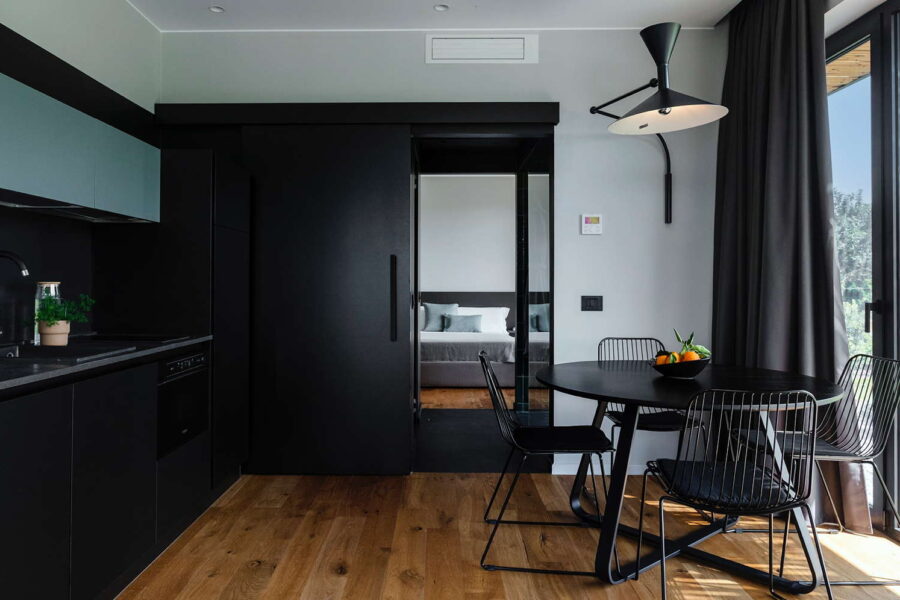 Stylish black kitchen and round dining table with garden view at Nature Luxe Cottage, one of the top Sicily villas with pool.