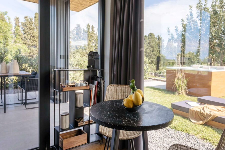Modern indoor breakfast nook with lemon centerpiece, opening to a sunny garden and jacuzzi at Nature Luxe Cottage, Sicily.