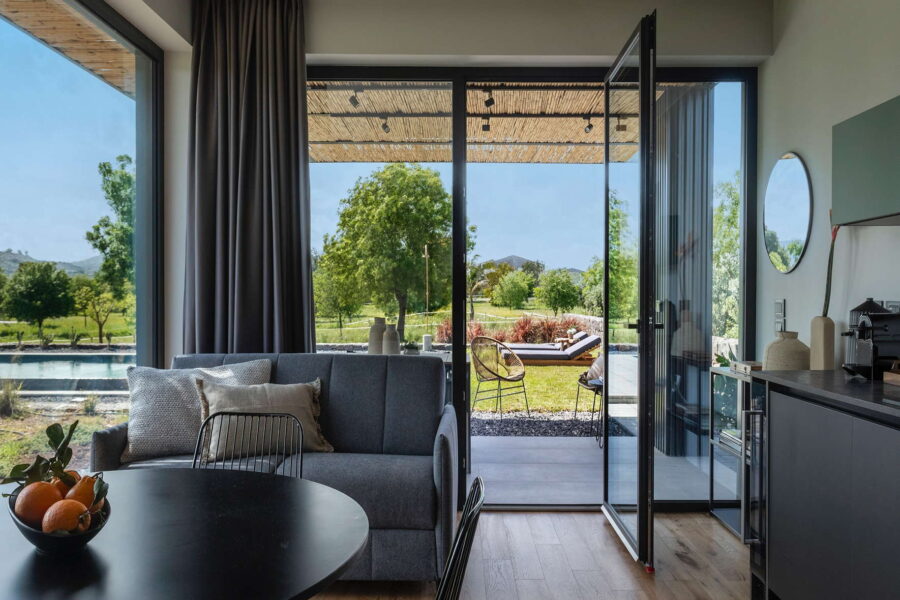 Bright living room with large glass doors opening to a private garden and pool view at Nature Luxe Cottage, Sicily.