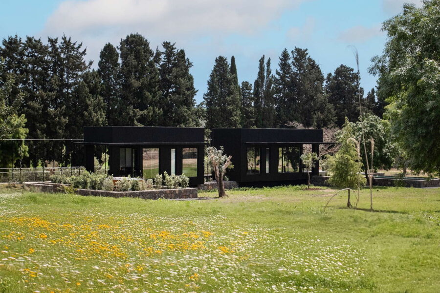 NatureLuxeCottage-SyracuseArea- -NatureEmbrace-ScentOfSicily Black modern villa surrounded by wildflowers, greenery, and trees at Nature Luxe Cottage, Sicily.