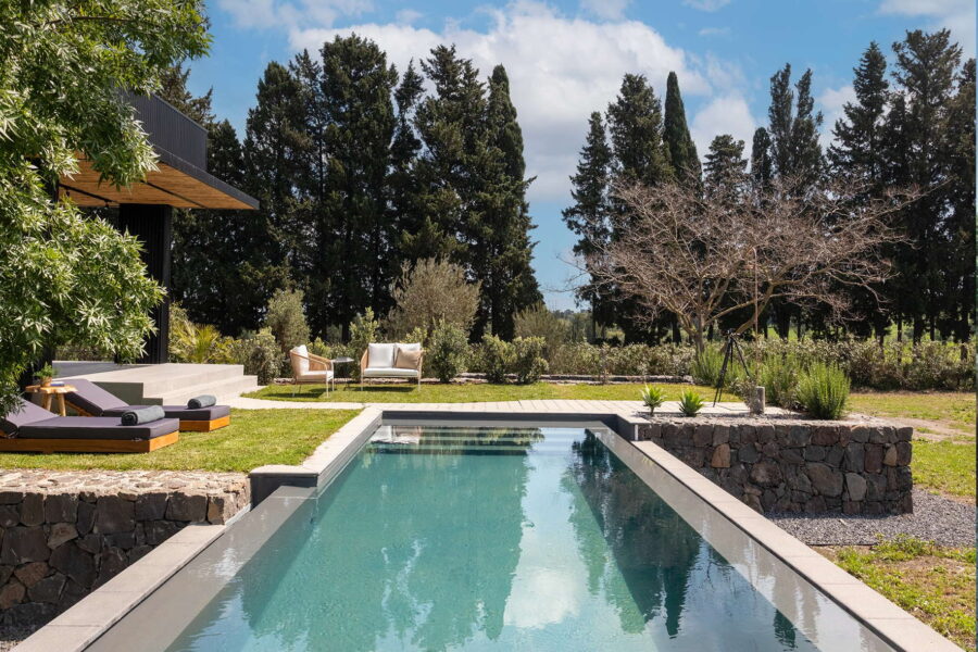 Modern rectangular pool surrounded by loungers, trees, and a garden seating area at Nature Luxe Cottage in Sicily.
