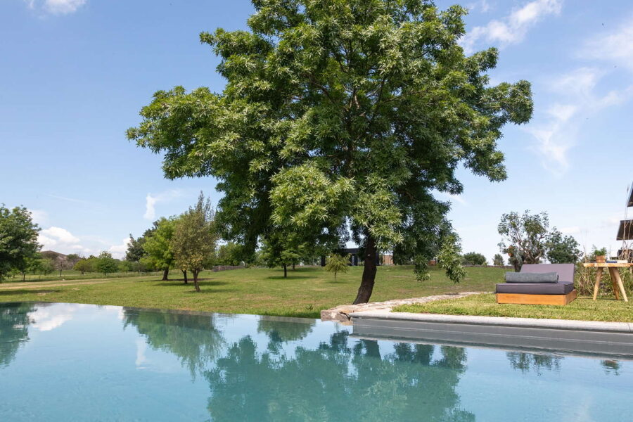 Infinity-edge pool beside lounge chairs and lush greenery at Nature Luxe Cottage, a stylish retreat among Sicily villas with pool.