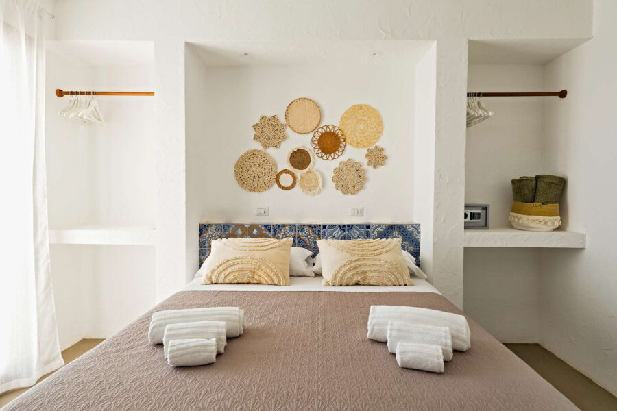 Elegant bedroom at Villa Brezza Marina in Scopello with Sicilian ceramic headboard, straw wall decorations, neutral tones and refined details – Sicily Luxury Villas and Sicily villas with pool