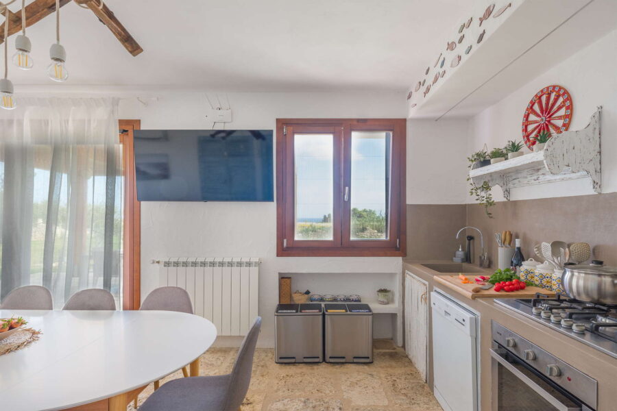 Bright kitchen at Villa Brezza Marina in Scopello with wooden window frames, stone flooring, modern appliances and Sicilian décor – Sicily Luxury Villas and Sicily villas with pool