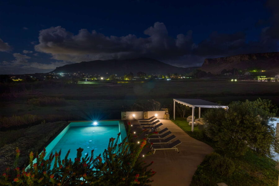 Evening view of private pool at Villa Brezza Marina in Scopello with illuminated water, countryside and mountain backdrop – Sicily Luxury Villas and Sicily villas with pool