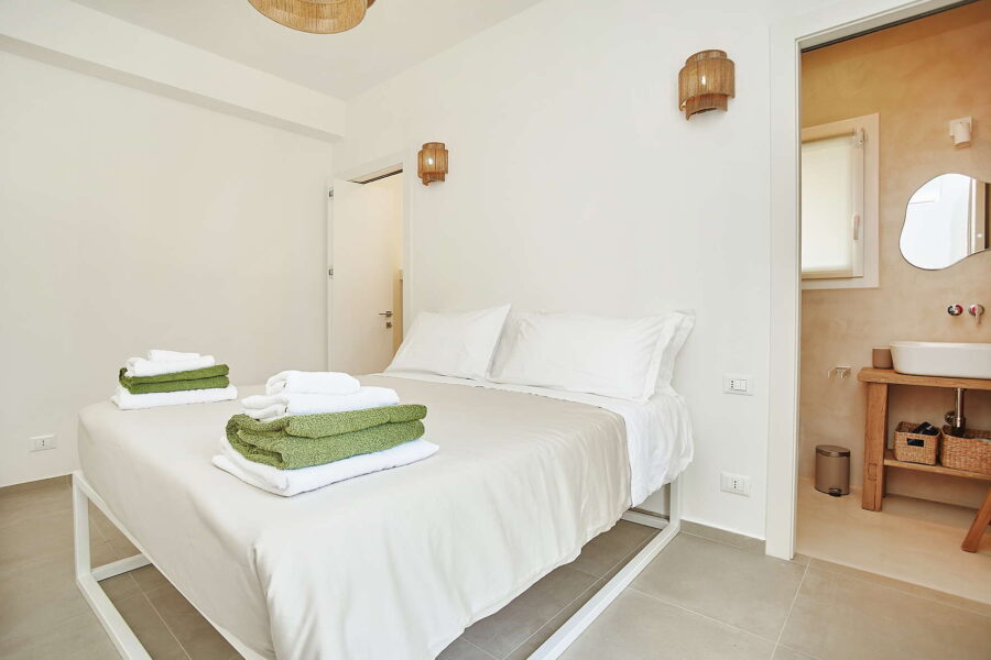Elegant bedroom in Sicily Luxury Villas with double bed, folded towels, ensuite bathroom and minimalist decor at Villa White Horizon, Sicily villas with pool