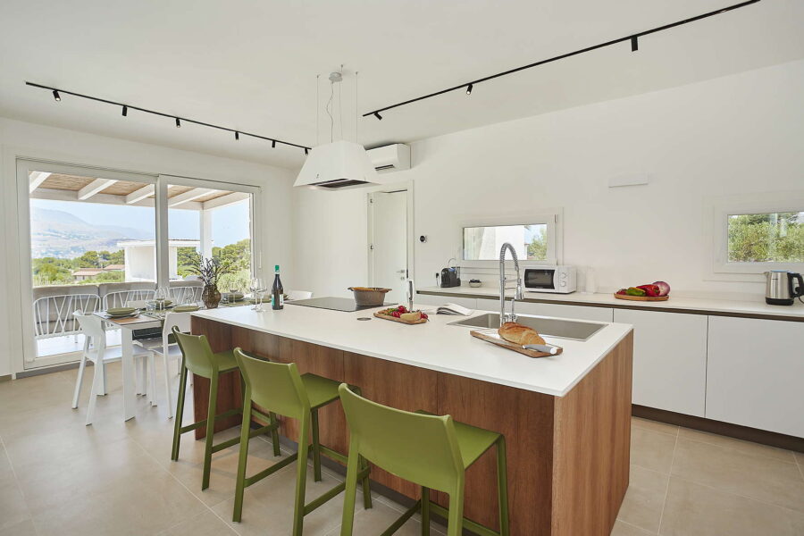 Modern open-plan kitchen with island, terrace view and natural light in Sicily Luxury Villas – Villa White Horizon, Sicily villas with pool