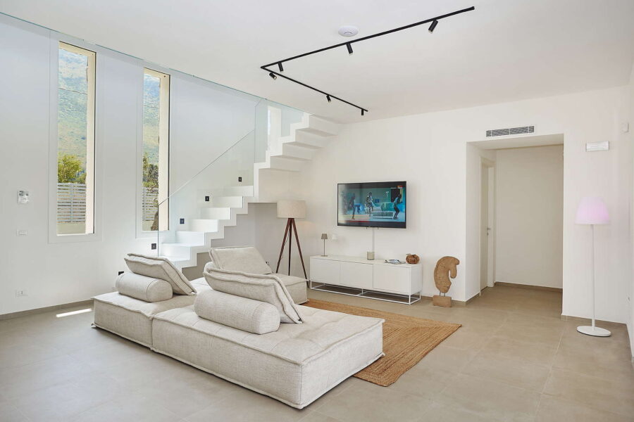 Modern living room with glass staircase, neutral sofa and natural light in Sicily Luxury Villas – Villa White Horizon, Sicily villas with pool