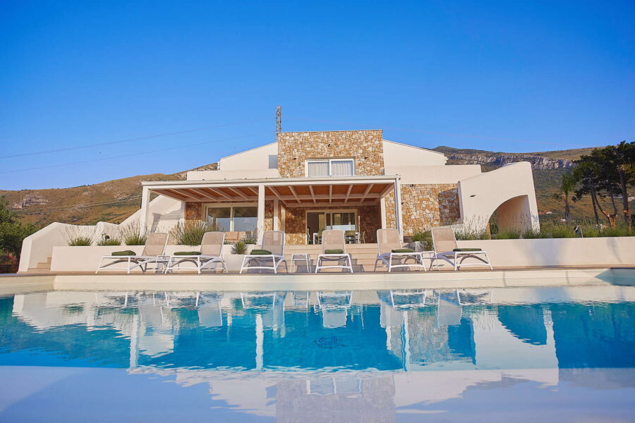 Sicily Luxury Villas – modern Sicily villa with pool at Villa White Horizon in Castellammare del Golfo, featuring sun loungers, stone façade, and panoramic mountain views