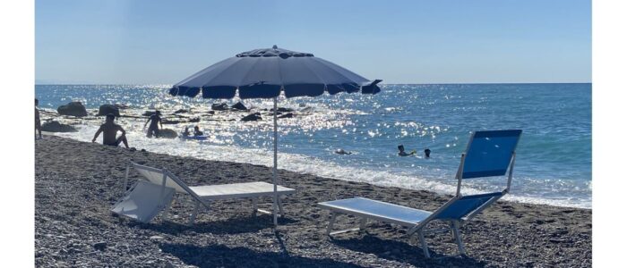 Sun loungers and umbrella on the beach near Villa Orlaya, one of the Sicily villas with pool offering easy access to the Sicilian coastline and crystal-clear sea.