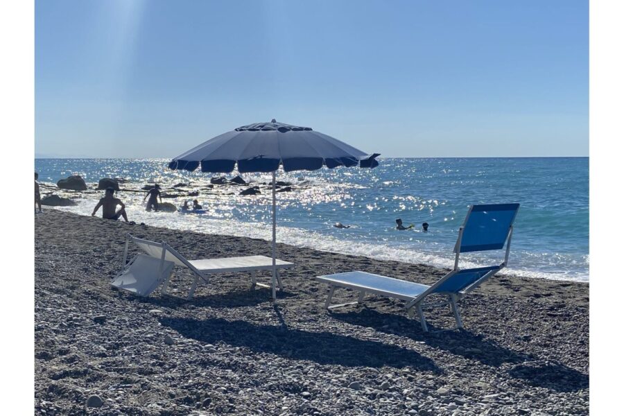 VillaOrlaya-Capo-di-Orlando-BluSea-ScentOfSicily Sun loungers and umbrella on the beach near Villa Orlaya, one of the Sicily villas with pool offering easy access to the Sicilian coastline and crystal-clear sea.