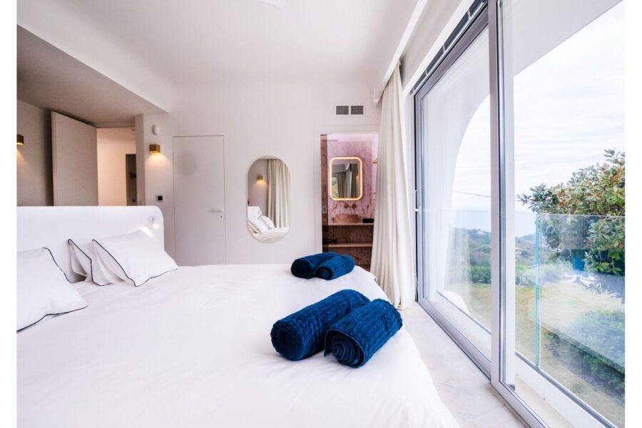 Villa Orlaya Panoramic Bedroom Suite | Sicily Luxury Villas with Sea View Bright bedroom suite with panoramic windows and en suite bathroom at Villa Orlaya, a luxury Sicily villa with pool and contemporary coastal interiors.