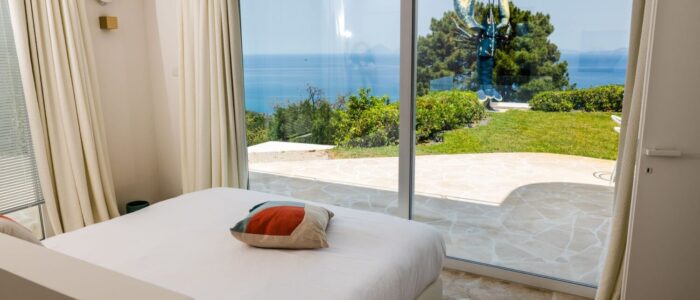 Modern double bedroom with sea view terrace at Villa Orlaya, one of the Sicily villas with pool featuring elegant interiors and panoramic coastal views in Sicily.
