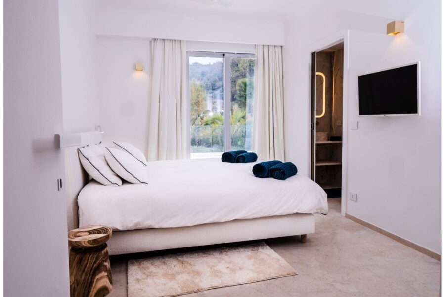 VillaOrlaya-Capo-di-Orlando-DoubleBedroomEnsuite-ScentOfSicily Contemporary double bedroom with en suite bathroom at Villa Orlaya, a refined Sicily villa with pool featuring elegant interiors and garden views.