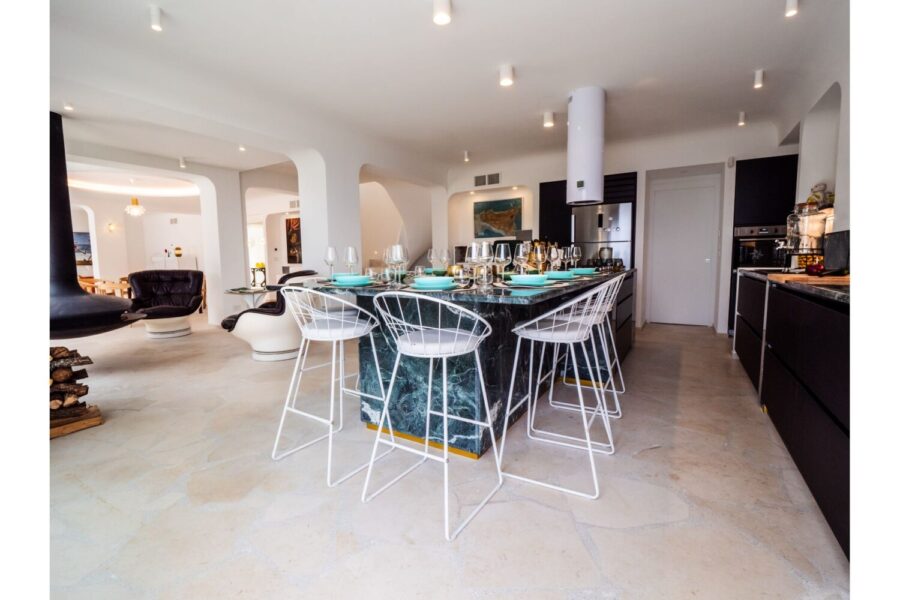 VillaOrlaya-Capo-di-Orlando-KitchenCornerView-ScentOfSicily Modern open kitchen and dining area at Villa Orlaya, a stylish Sicily villa with pool featuring marble finishes, contemporary interiors, and spacious living areas.