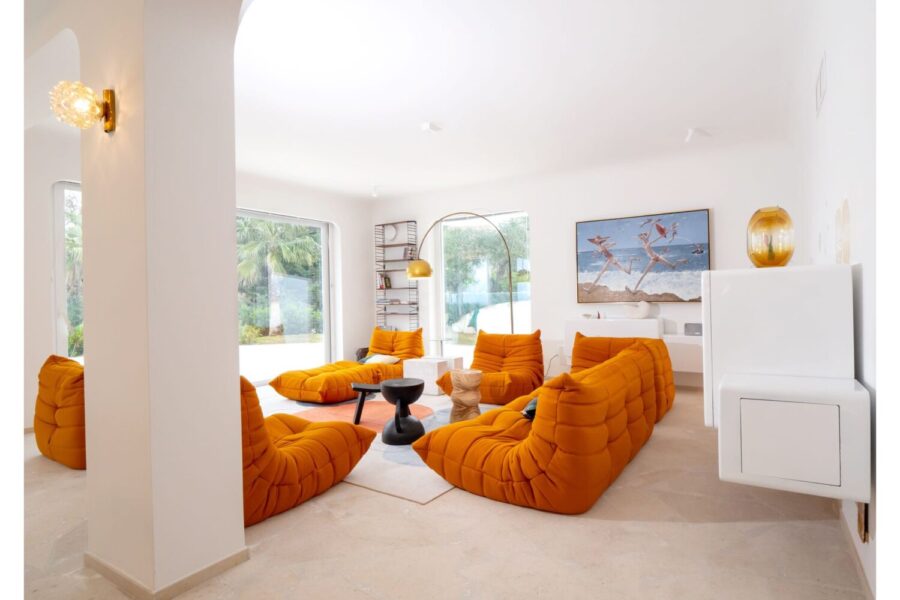 VillaOrlaya-Capo-di-Orlando-OrangeLivingRoom-ScentOfSicily Contemporary orange living room at Villa Orlaya, a luxury Sicily villa with pool featuring designer seating, modern décor, and bright open interiors.