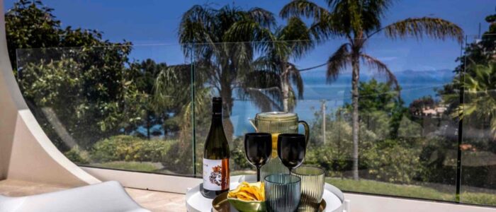 VillaOrlaya-Capo-di-Orlando-TerraceView-ScentOfSicily Sea view terrace at Villa Orlaya with wine, outdoor seating, and tropical garden views, Sicily villas with pool by Scent of Sicily