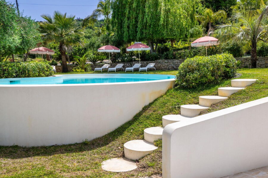 VillaOrlaya-Capo-di-Orlando-ToPatio-ScentOfSicily Villa Orlaya garden and swimming pool with palm trees, sun loungers, and Mediterranean greenery in Sicily, Sicily villas with pool by Scent of Sicily